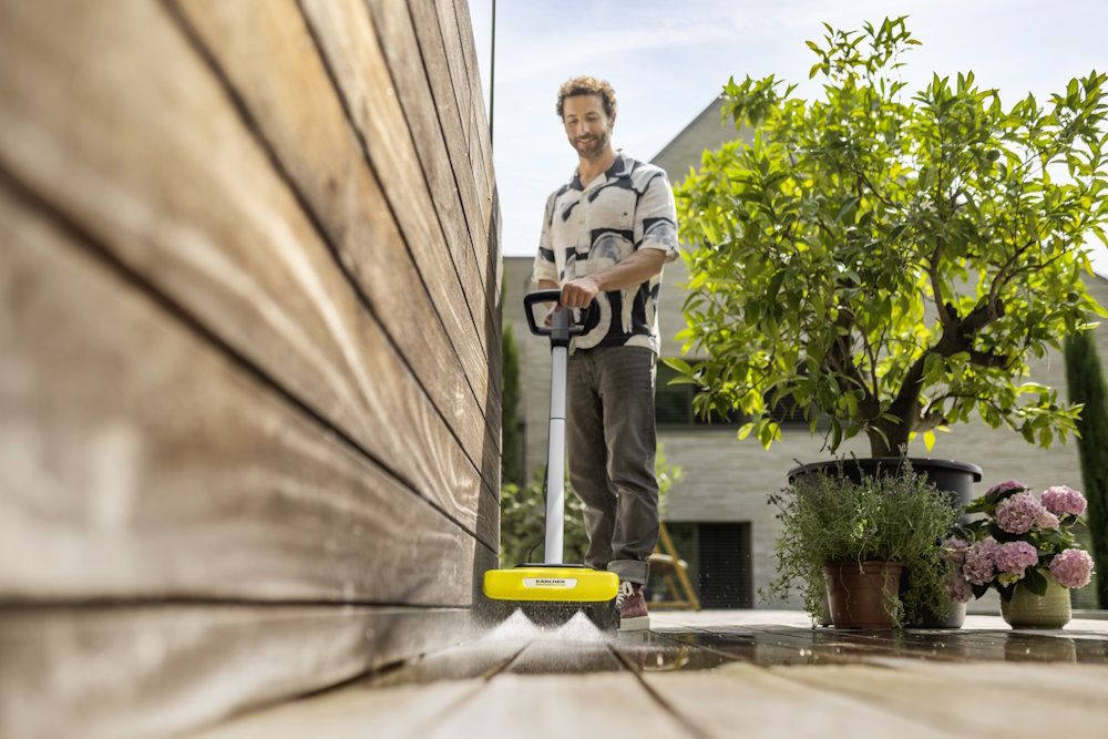 Person reinigt Holzterrasse mit Flächenreiniger